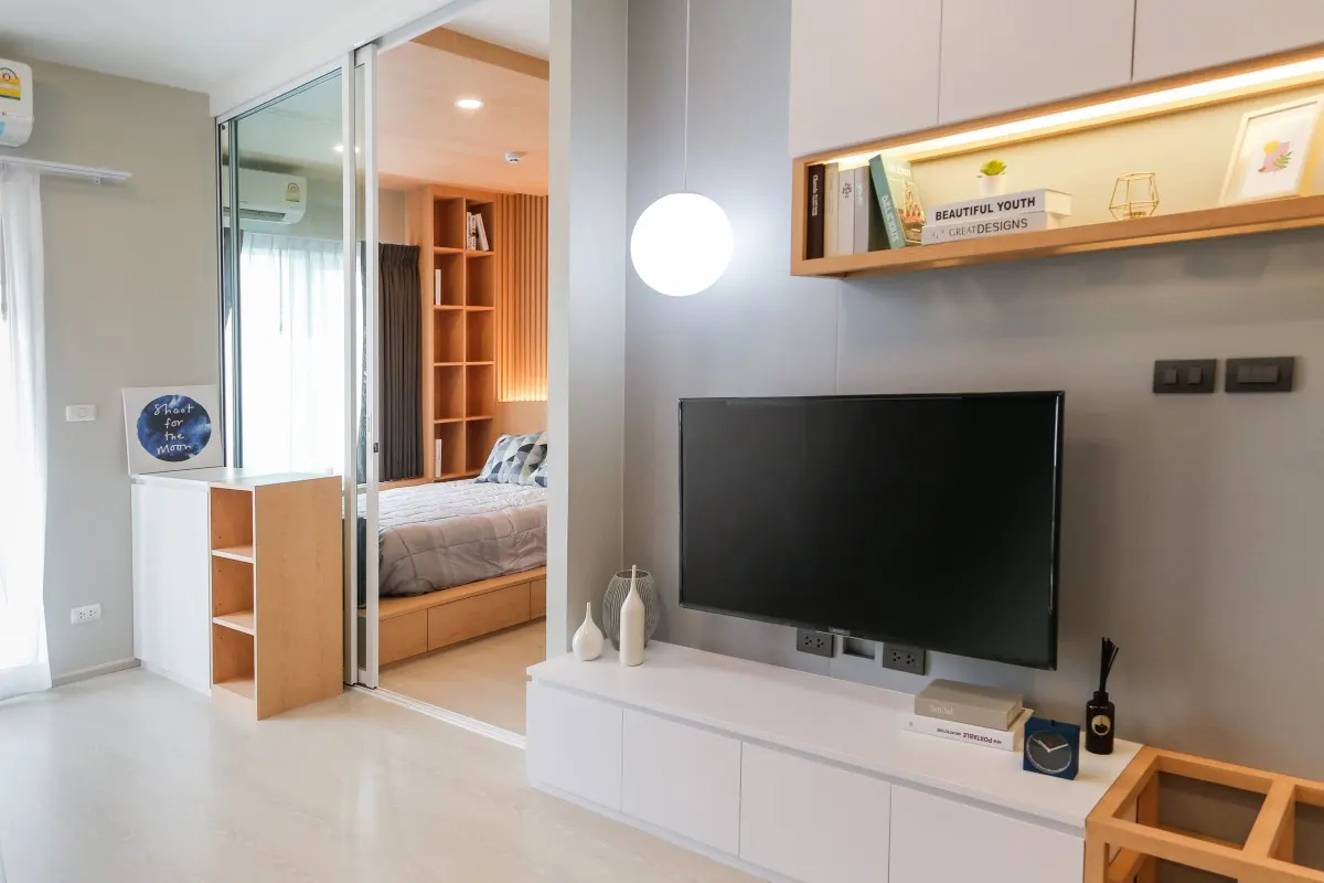 ห้องนั่งเล่นคอนโด Eco Chapter One Ratchada มุมทีวีบิวท์อินและโคมไฟแขวนทรงกลม ผลงานออกแบบภายในโดย OBJ Design & Build