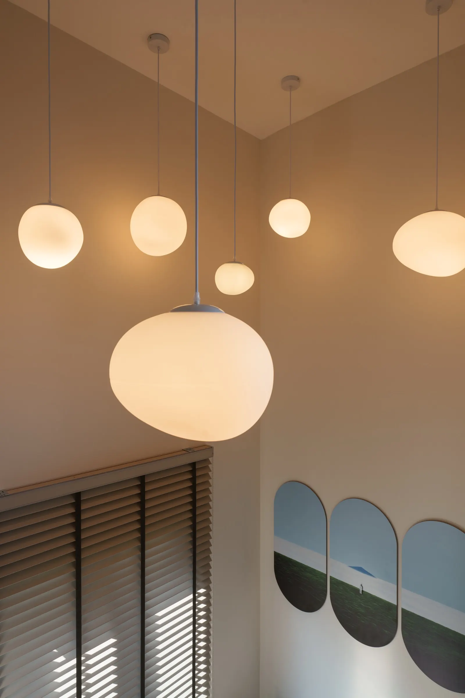 โคมไฟแขวนทรงกลมกระจายหลายดวง เหนือชานพักบันได ผลงานออกแบบภายในโดย OBJ Design & Build